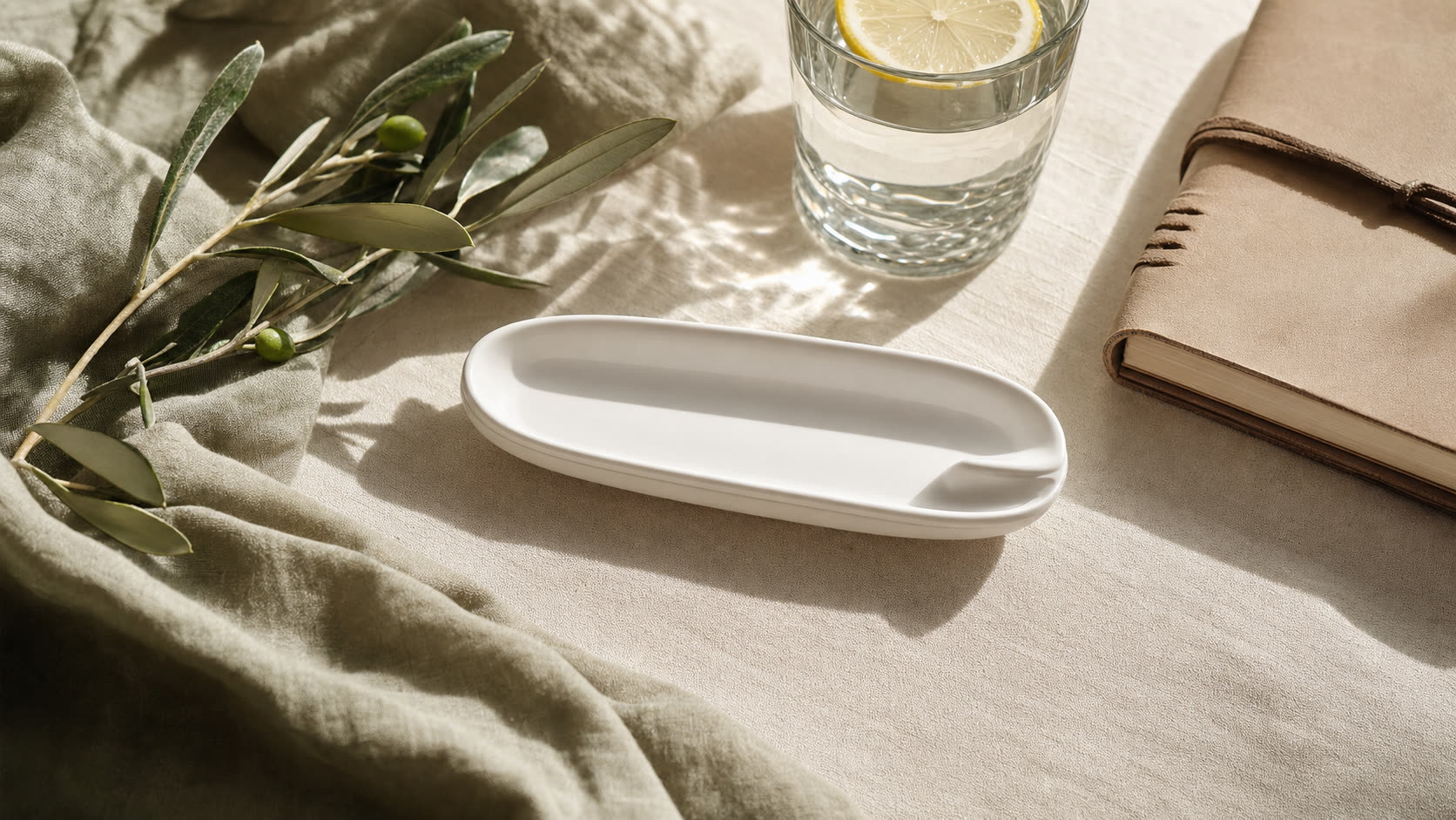 Editorial flat lay: empty ceramic dish with olive branch and journal representing GLP-1 discontinuation